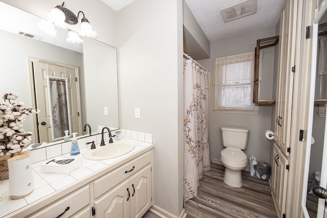 full bathroom featuring toilet, visible vents, a textured ceiling, and wood finished floors