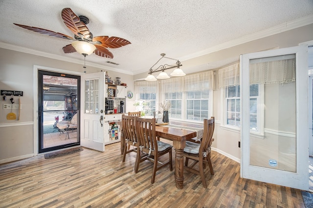 dining area featuring a textured ceiling, ceiling fan, wood finished floors, visible vents, and crown molding