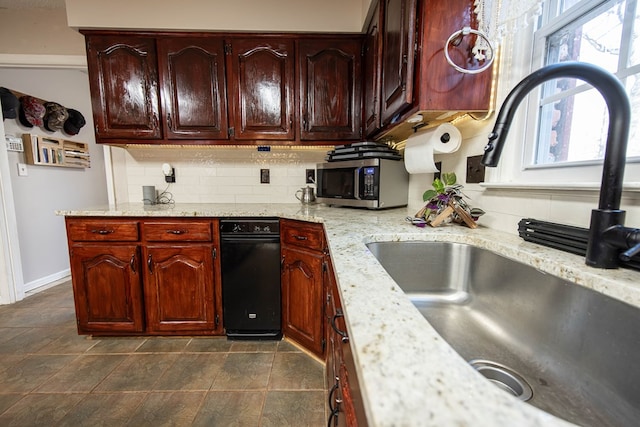 kitchen with light stone counters, a sink, baseboards, backsplash, and stainless steel microwave