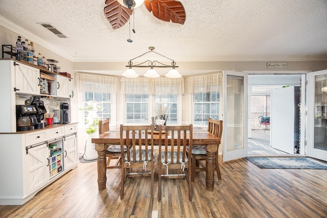 dining area with crown molding, ceiling fan, visible vents, and light wood-style floors