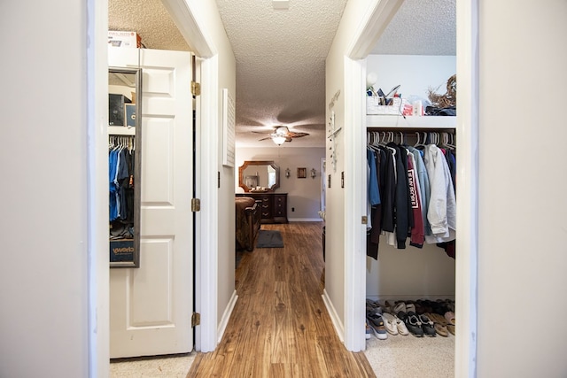 hall with baseboards, a textured ceiling, and wood finished floors