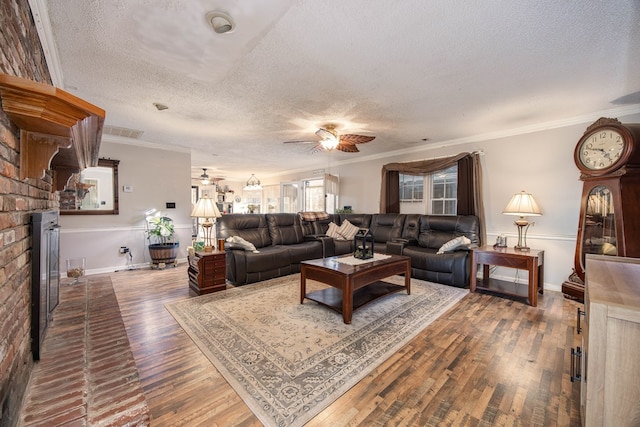 living area featuring a textured ceiling, hardwood / wood-style flooring, a fireplace, a ceiling fan, and ornamental molding