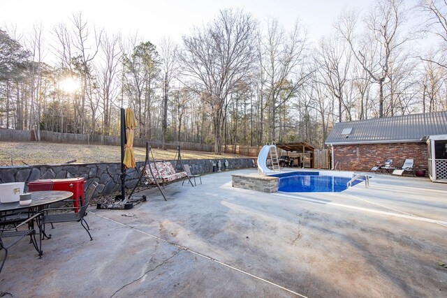 view of pool featuring a fenced in pool, a fenced backyard, outdoor dining area, a water slide, and a patio area