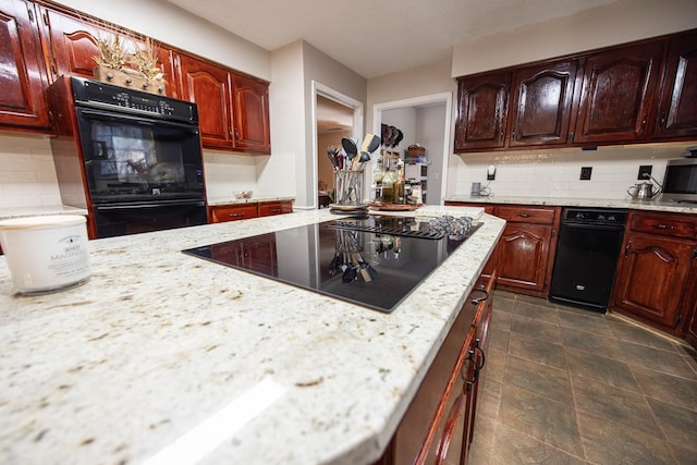 kitchen featuring light stone countertops, black appliances, and backsplash