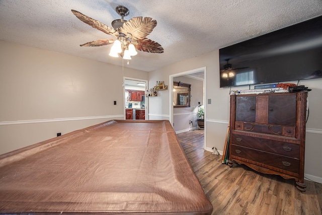 bedroom with baseboards, a textured ceiling, a ceiling fan, and wood finished floors