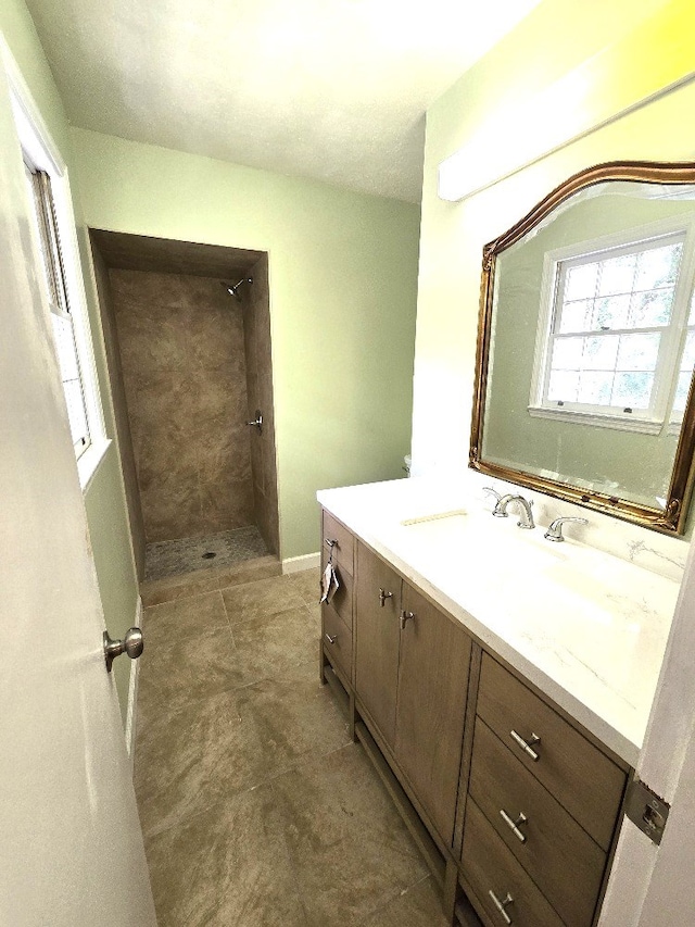 full bathroom featuring a tile shower and vanity