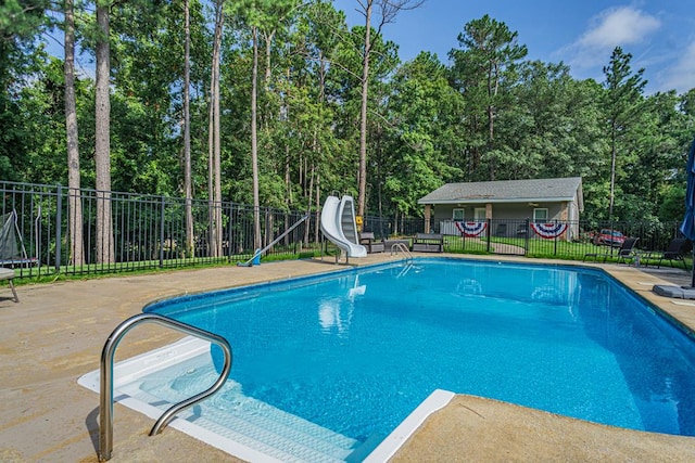 view of pool with an outbuilding, a water slide, and a patio