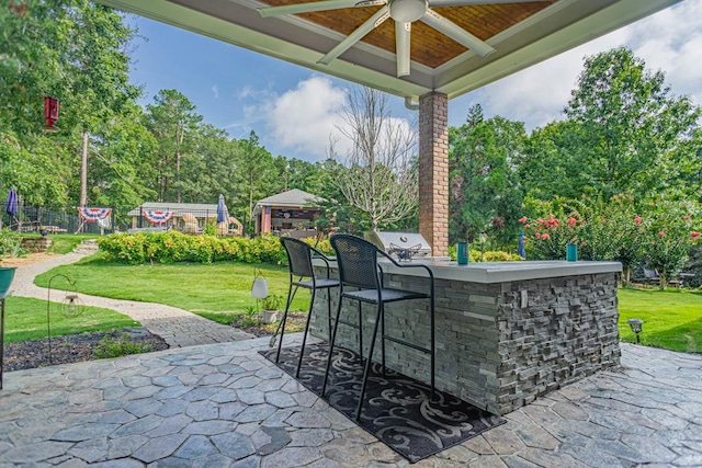 view of patio / terrace featuring ceiling fan, an outdoor bar, and grilling area