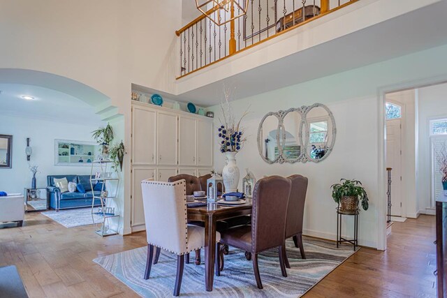 dining room featuring a towering ceiling, light hardwood / wood-style floors, and a wealth of natural light