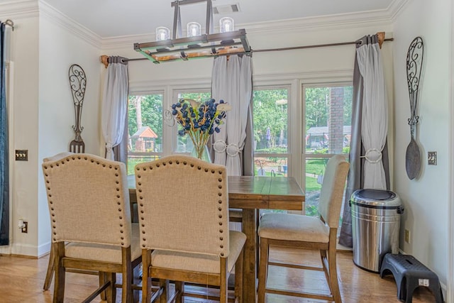 dining space with hardwood / wood-style floors, a healthy amount of sunlight, and crown molding