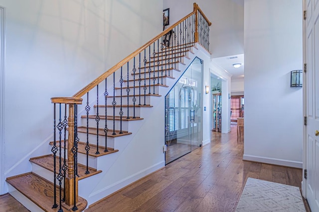 stairway featuring a high ceiling and hardwood / wood-style flooring