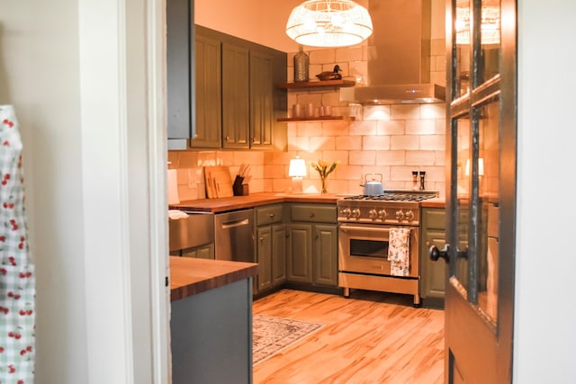 kitchen featuring exhaust hood, light hardwood / wood-style flooring, appliances with stainless steel finishes, tasteful backsplash, and butcher block counters