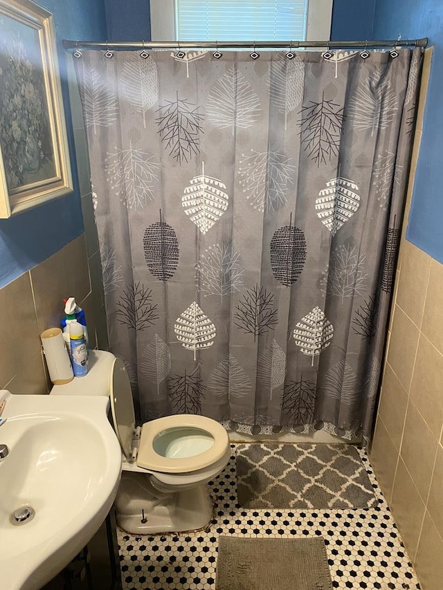 bathroom featuring tile patterned floors, sink, tile walls, and toilet