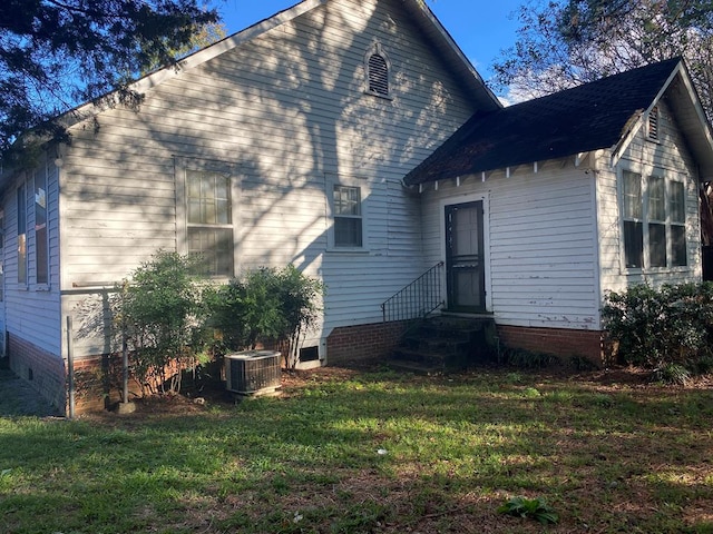 back of property featuring a yard and central AC