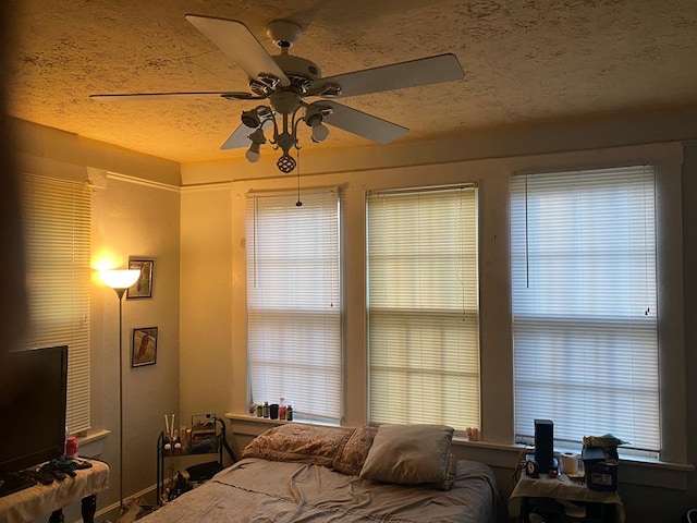 bedroom featuring ceiling fan, a textured ceiling, and multiple windows