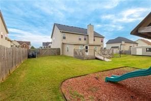 back of property featuring a lawn, a storage unit, a deck, and a playground