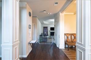 corridor with ornate columns and dark wood-type flooring