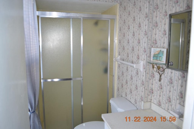 bathroom featuring vanity, an enclosed shower, and toilet