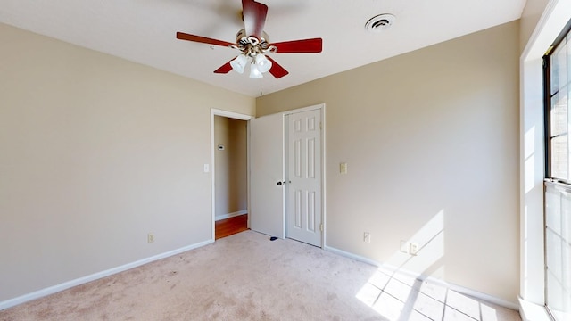 unfurnished bedroom featuring visible vents, light carpet, baseboards, and a closet