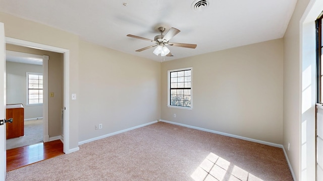 carpeted spare room featuring visible vents, plenty of natural light, baseboards, and ceiling fan