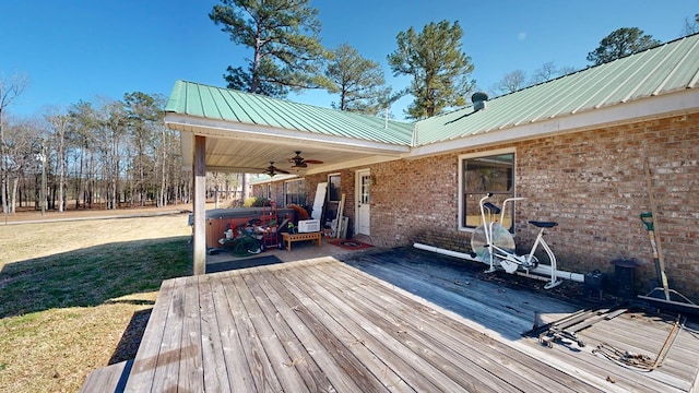 wooden terrace featuring ceiling fan, a yard, and a hot tub