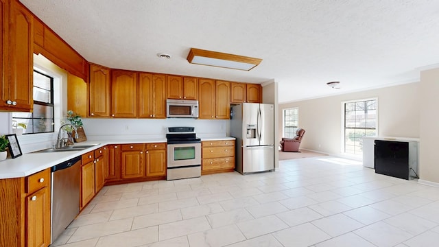 kitchen with a sink, ornamental molding, light countertops, stainless steel appliances, and brown cabinets