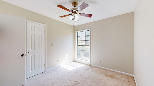 spare room featuring carpet, baseboards, and ceiling fan