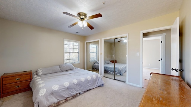 bedroom featuring two closets, ceiling fan, baseboards, carpet floors, and a textured ceiling