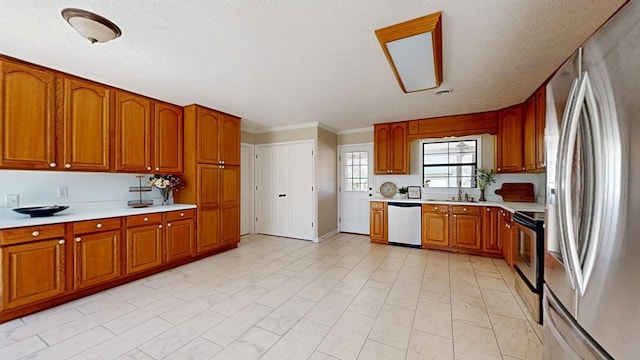 kitchen with a sink, stainless steel appliances, brown cabinetry, and light countertops