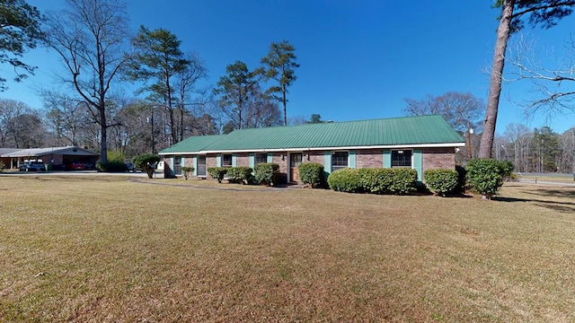 ranch-style home with brick siding, metal roof, a carport, and a front yard