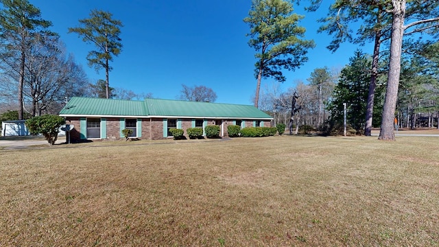 ranch-style house with brick siding, metal roof, and a front lawn