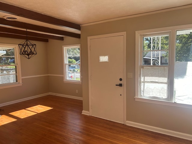 foyer entrance with beam ceiling, wood finished floors, baseboards, and a textured ceiling