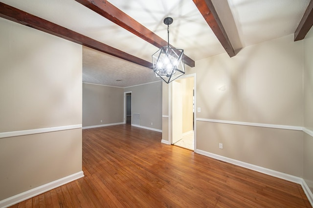 unfurnished room with visible vents, baseboards, a chandelier, hardwood / wood-style floors, and beam ceiling