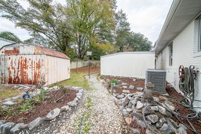 view of yard featuring fence, an outbuilding, central AC unit, and a shed