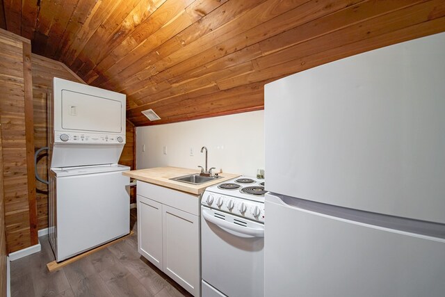 kitchen featuring white appliances, stacked washer and clothes dryer, sink, vaulted ceiling, and white cabinetry