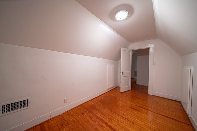 additional living space with light hardwood / wood-style floors and vaulted ceiling