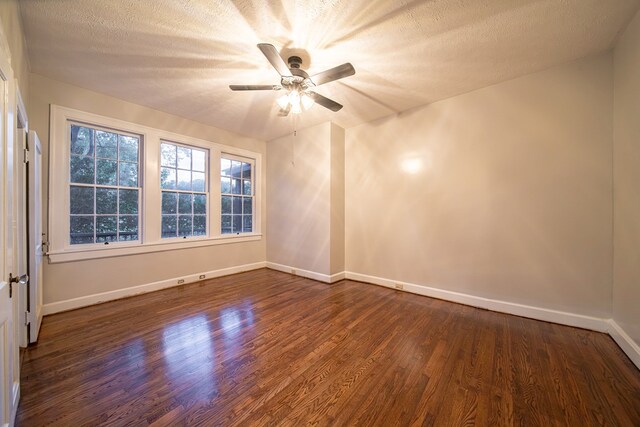 empty room with a textured ceiling, dark hardwood / wood-style floors, and ceiling fan