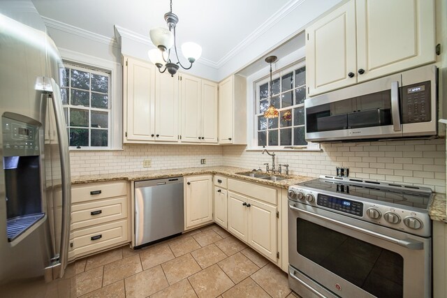 kitchen featuring backsplash, sink, hanging light fixtures, ornamental molding, and stainless steel appliances