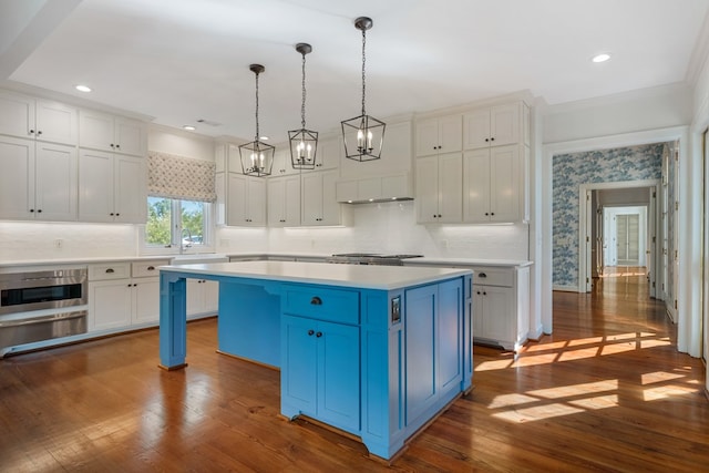 kitchen with a center island, white cabinets, hanging light fixtures, dark hardwood / wood-style floors, and blue cabinetry