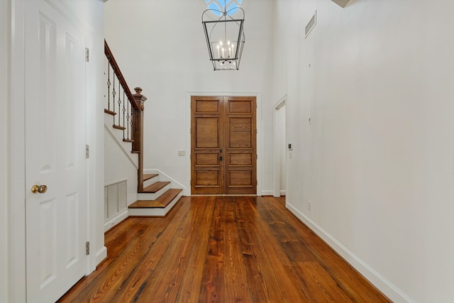 entryway featuring a high ceiling, dark wood-type flooring, and a notable chandelier