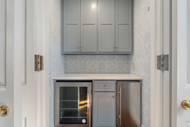 bar with gray cabinetry, stainless steel refrigerator, wine cooler, and tasteful backsplash