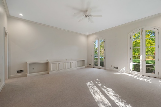 carpeted empty room with ceiling fan, crown molding, and french doors