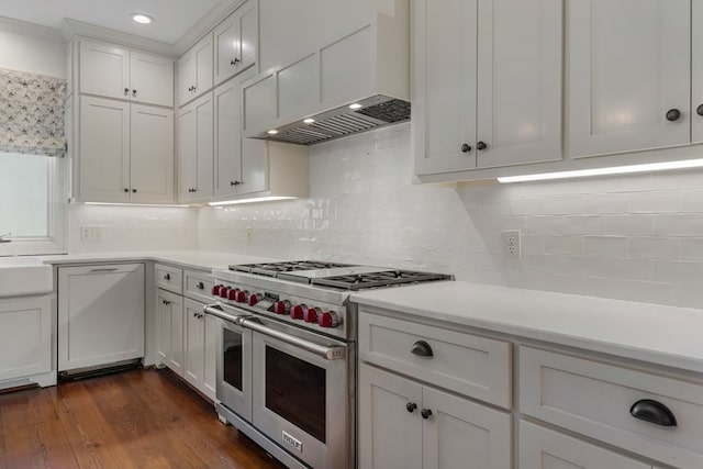 kitchen with white cabinets, range with two ovens, wall chimney range hood, decorative backsplash, and dark hardwood / wood-style flooring