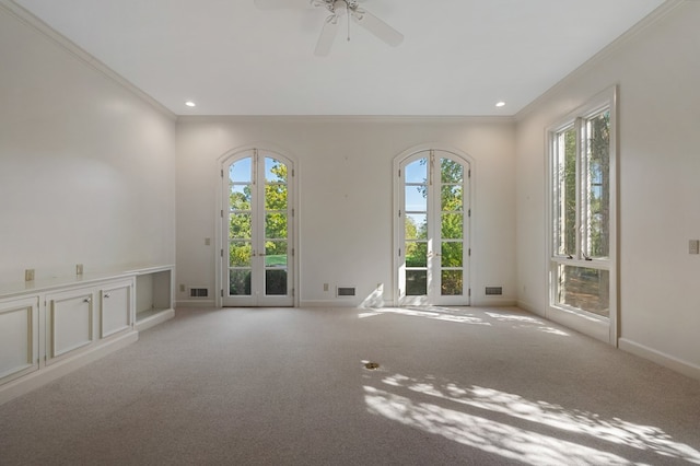 carpeted empty room featuring french doors, plenty of natural light, and crown molding