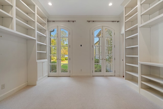 doorway to outside with light carpet, french doors, and ornamental molding