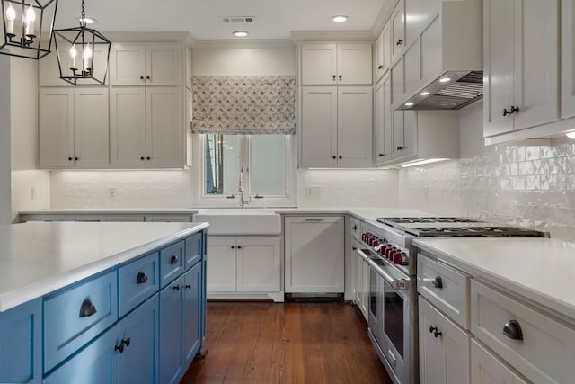 kitchen with white cabinets, range with two ovens, wall chimney range hood, hanging light fixtures, and blue cabinetry