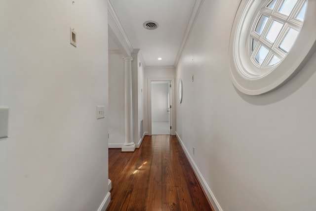 hallway featuring dark hardwood / wood-style floors, decorative columns, and crown molding