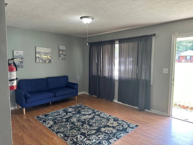 living room with hardwood / wood-style flooring, a healthy amount of sunlight, and a textured ceiling