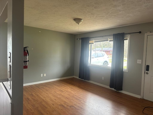 foyer entrance featuring a textured ceiling, wood finished floors, and baseboards