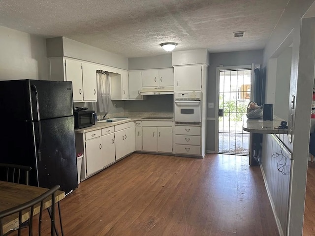 kitchen with sink, hardwood / wood-style flooring, black appliances, a textured ceiling, and white cabinets